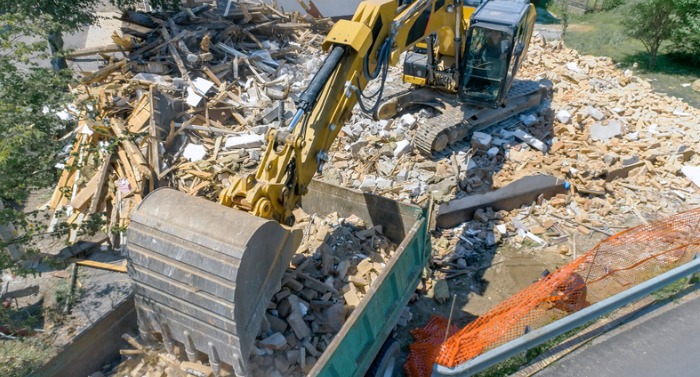 digger-placing-construction-waste-of-demolished-building-onto-a-truck-picture-id1128913421