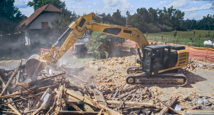 digger-tipping-over-outer-walls-of-building-being-demolished-picture-id1129582595