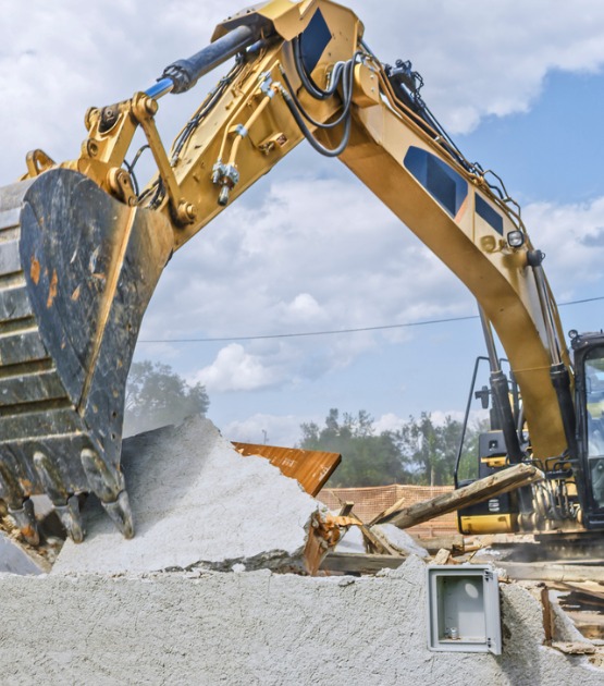digger-tipping-over-outer-walls-of-building-being-demolished-picture-id1129582636